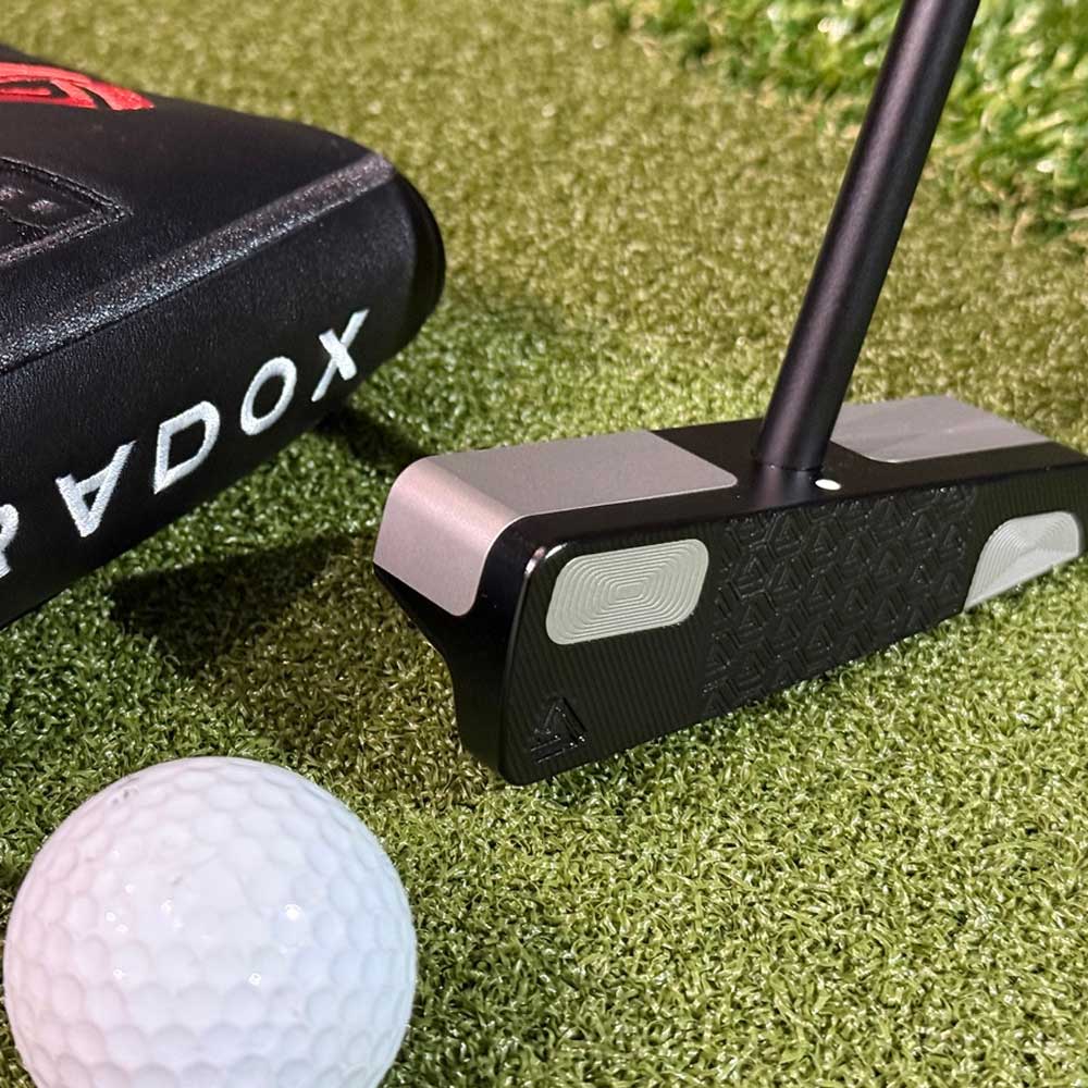 BGT Paradox Blade Putter Shaft, golf ball, and Odyssey putter case on a grass surface