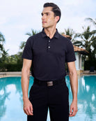 Close up of model in front of a pool wearing smart black golf performance polo called the Nantucket.