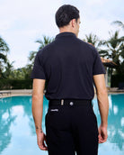 Back view of model in front of a pool wearing the nantucket performance polo in black. Premium fabric with cutting-edge materials.
