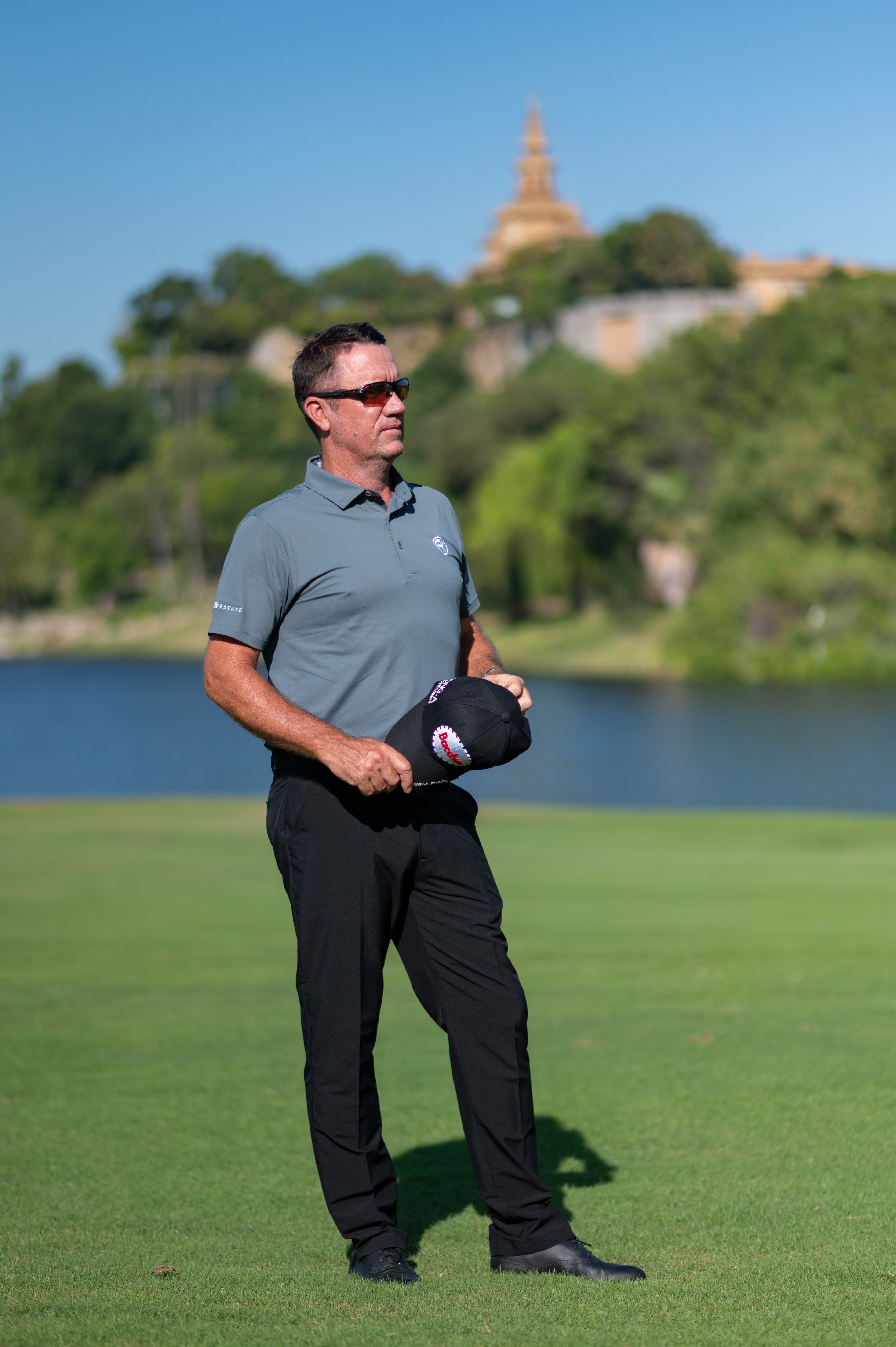 Full body image of golfer in the slate grey polo. Wearing the polo with black trousers designed for high-performance on the golf course.
