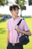 Boy on a golf course wearing the pink Nantucket Performance Polo. Designed with fabric technologies like sweat-wicking, 4-way stretch