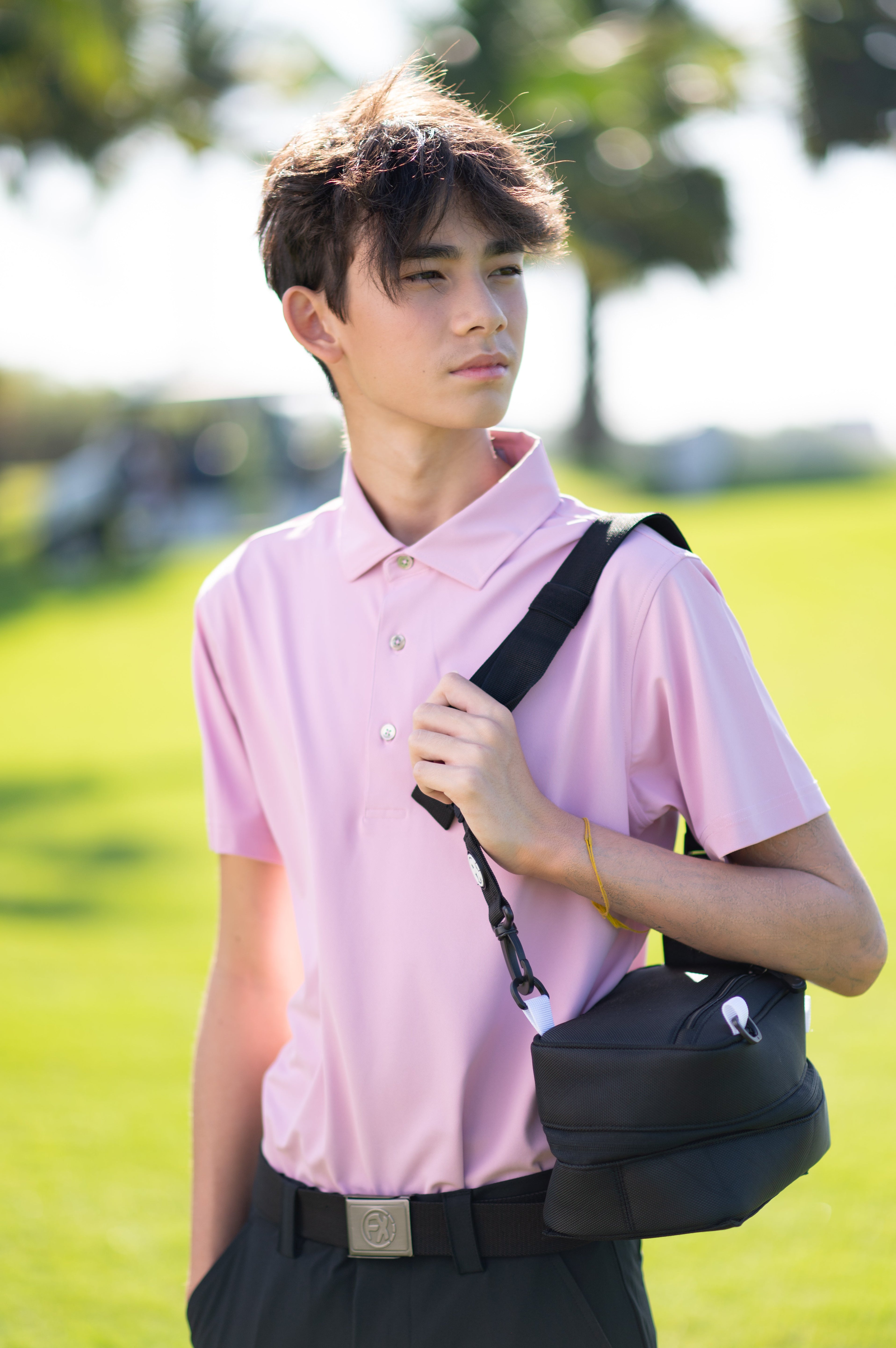 Boy on a golf course wearing the pink Nantucket Performance Polo. Designed with fabric technologies like sweat-wicking, 4-way stretch